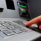 a hand is pressing a button on an atm machine.