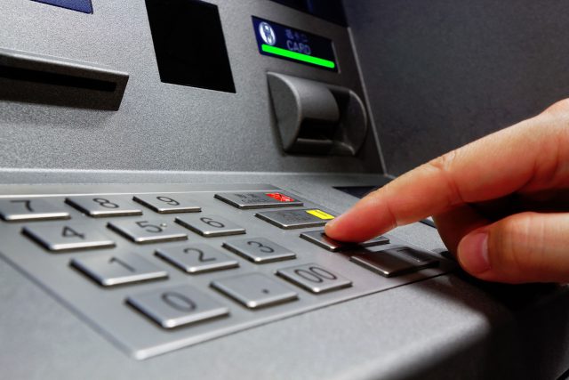 a hand is pressing a button on an atm machine.